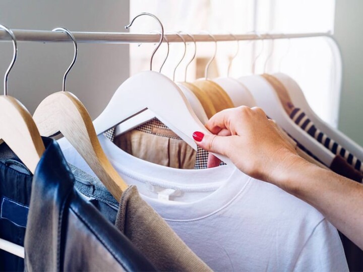 a woman's hand holding up an item clothing from a clothing rack
