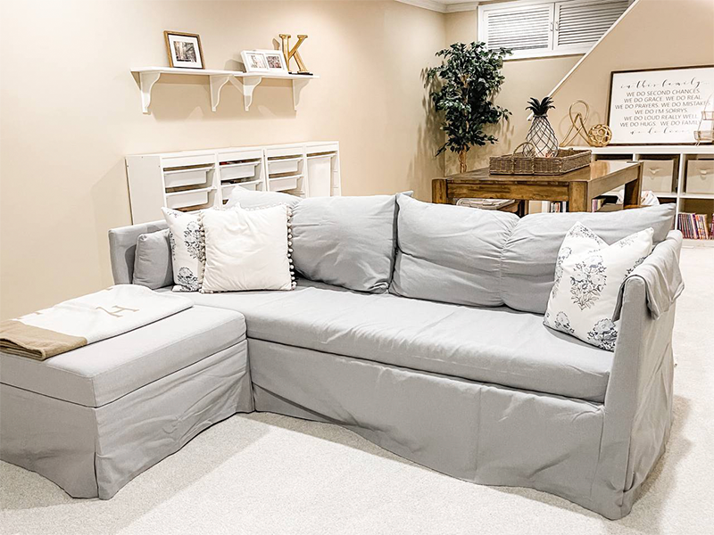 A gray couch in a basement | How to Create a Guest Room When You Don't Have One