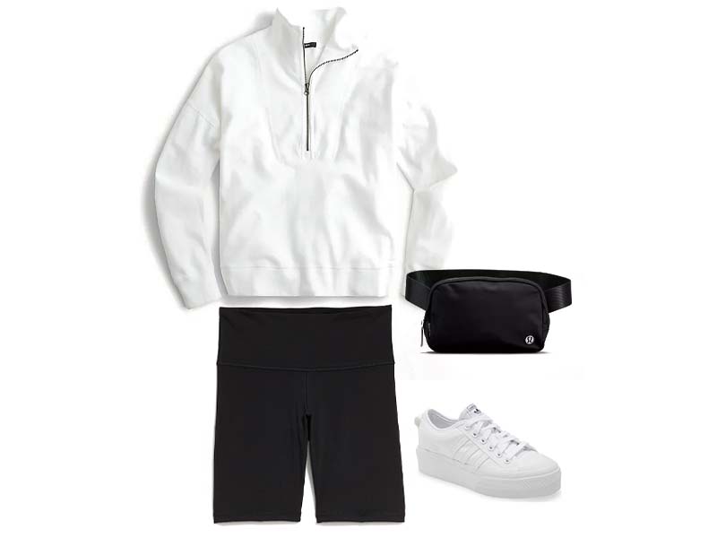 White half zip sweatshirt, black bike shorts, white platform sneakers, and a black belt bag