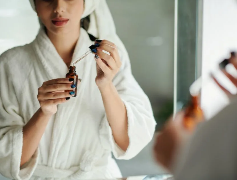 Applying vitamin C serum from a dropper to the skin