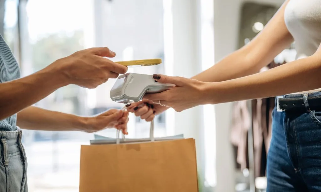 Woman paying for a clothing purchase, representing money already spent on clothes and shopping decisions