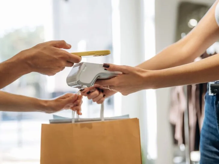 Woman paying for a clothing purchase, representing money already spent on clothes and shopping decisions