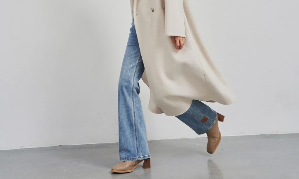 Woman wearing modern jeans and coat showing updated clothing proportions