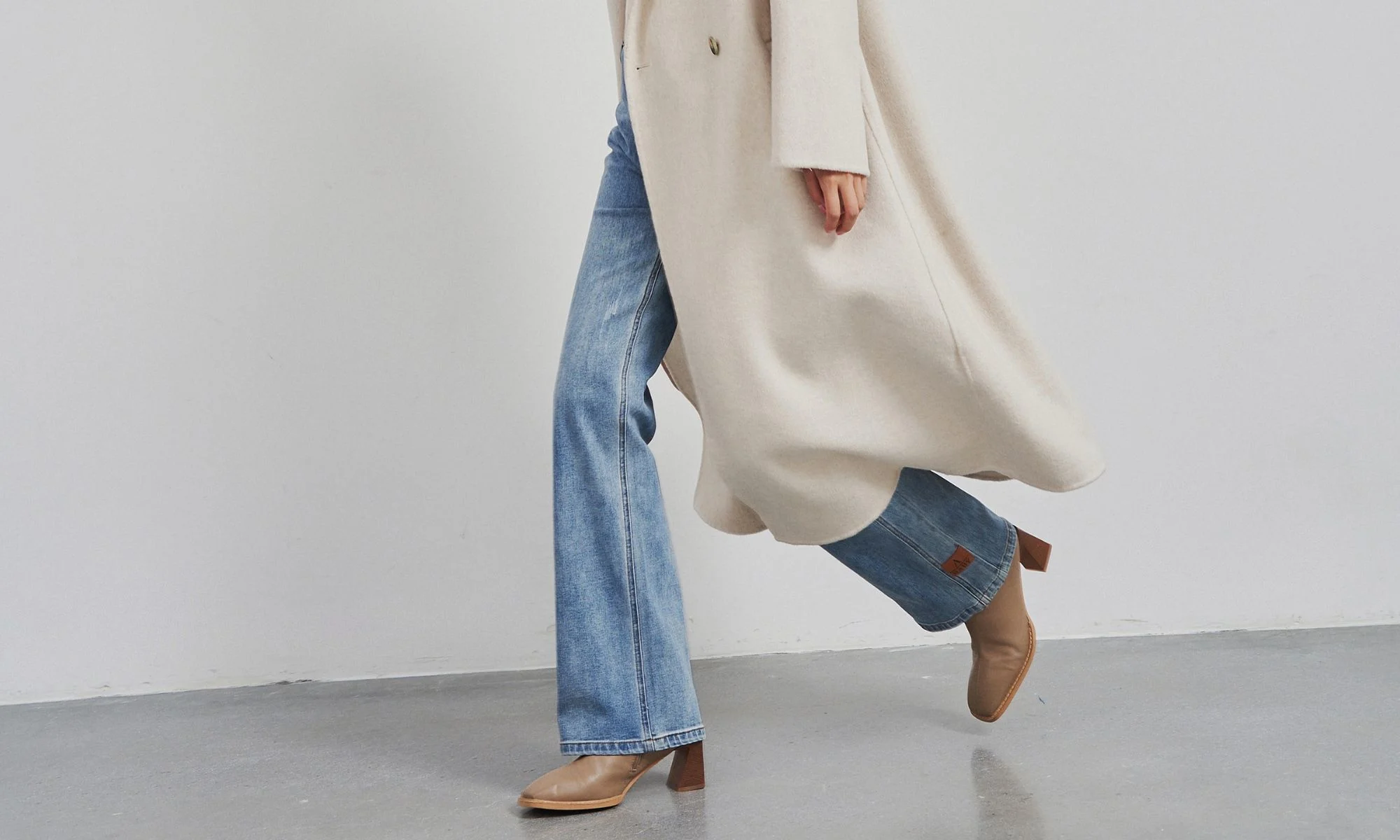 Woman wearing modern jeans and coat showing updated clothing proportions