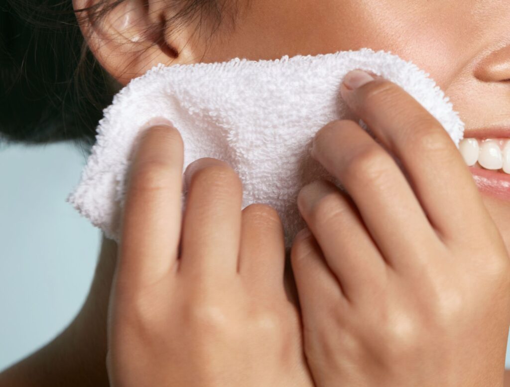 Using a warm washcloth during a morning skincare routine to smooth skin before makeup.
