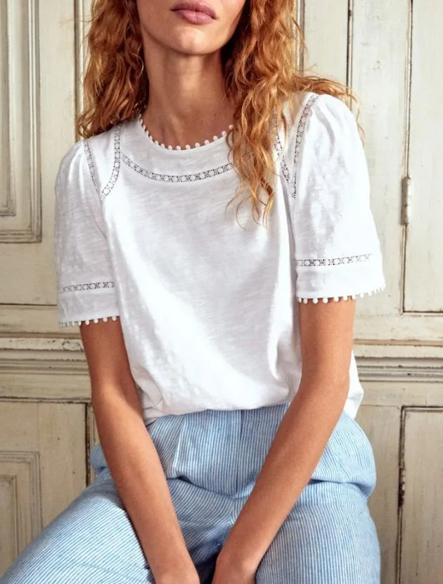 White Mila lace trim top from Boden styled for women over 40 with subtle pom-pom detail and puff sleeves