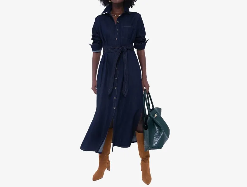 Woman wearing a dark wash denim shirt dress from Tuckernuck styled with tall boots and a green tote bag, a timeless denim trend for 2025.