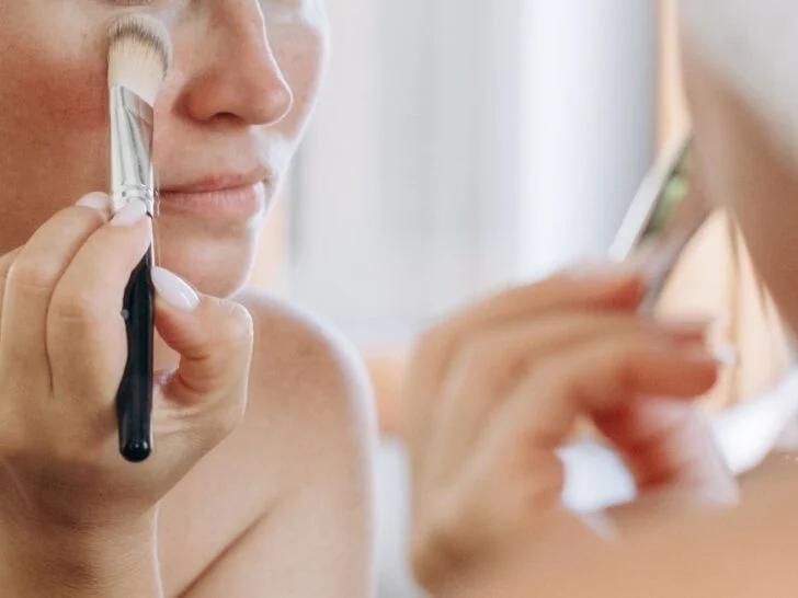 Applying concealer under the eyes with a brush for a smooth, natural-looking finish