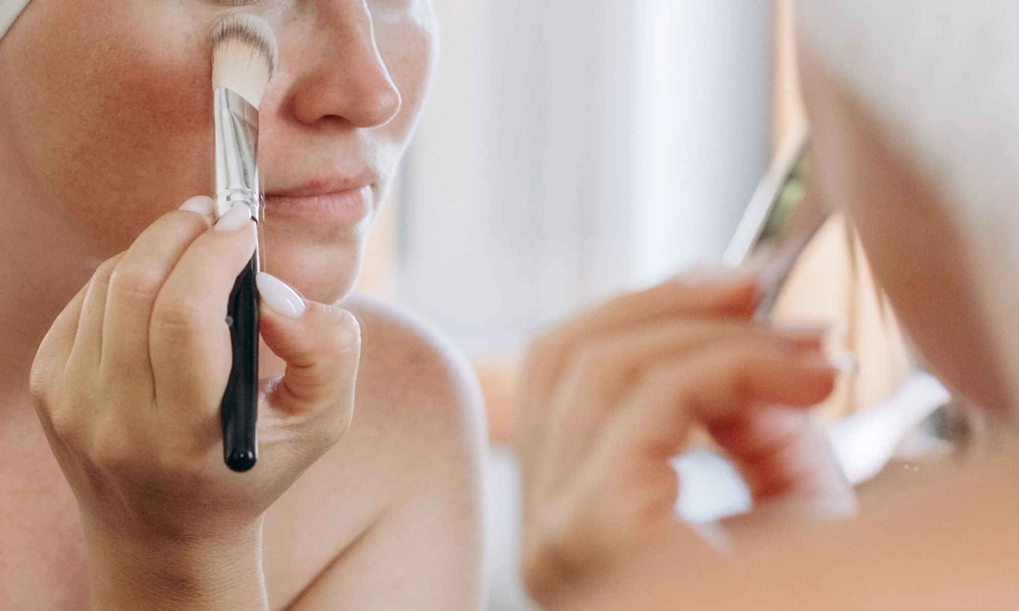 Applying concealer under the eyes with a brush for a smooth, natural-looking finish