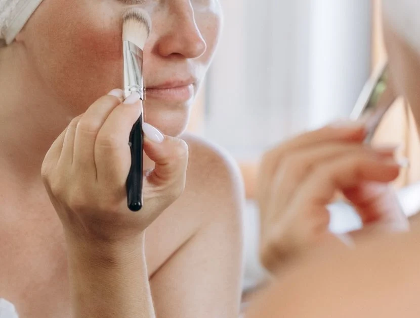 Applying concealer under the eyes with a brush for a smooth, natural-looking finish