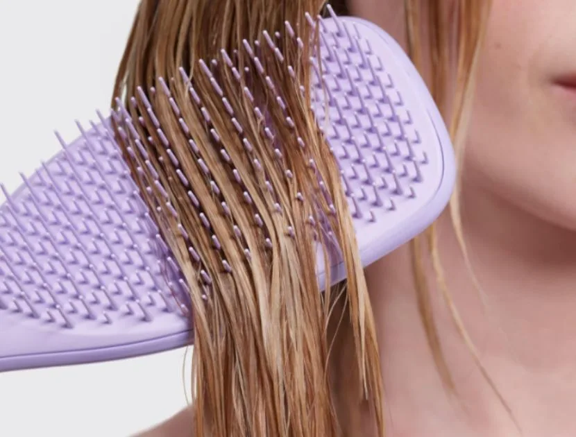 Detangling hair brush gently removing knots from wet hair to reduce breakage