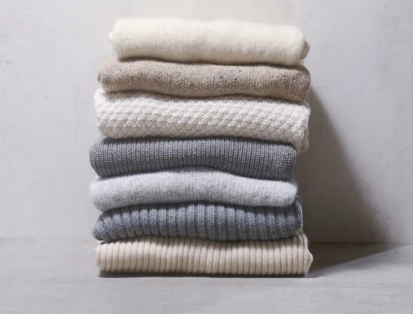 Stacked neutral sweaters showing proper knitwear care and storage to help sweaters last longer