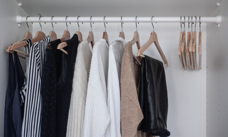 A neutral, edited wardrobe showing essential clothing pieces arranged in a calm, organized closet.