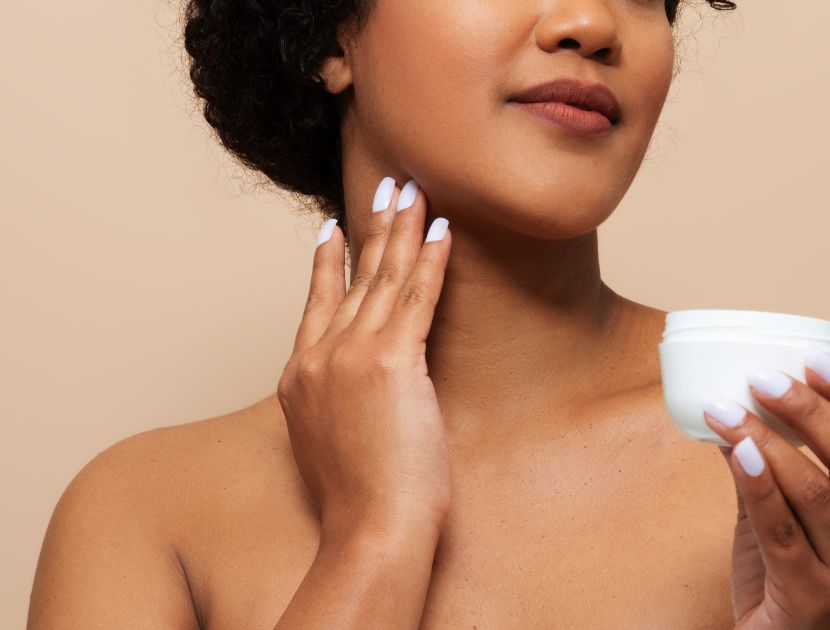 Woman in her 40s applying skincare to her jawline in natural light