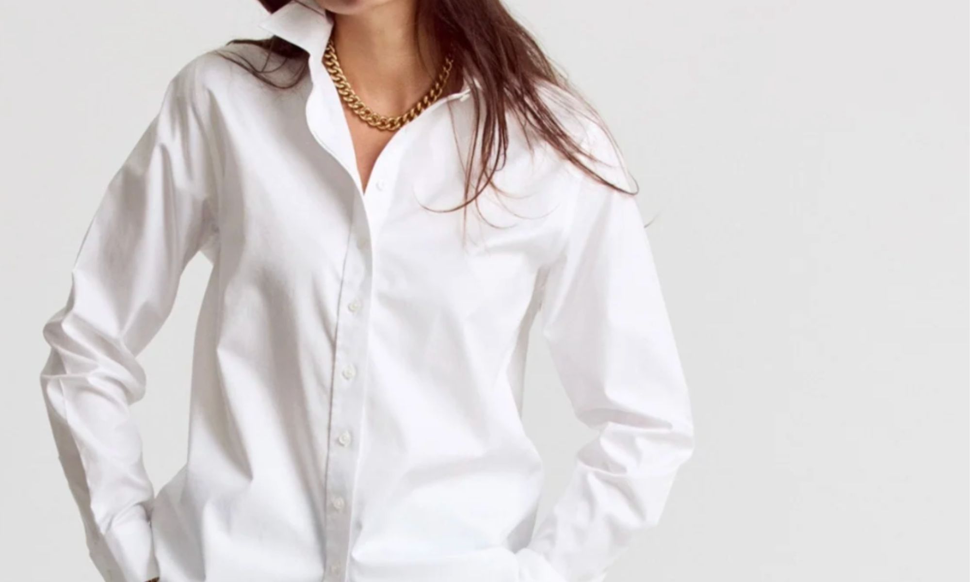 Oversized white button-down shirt styled with a gold chain necklace