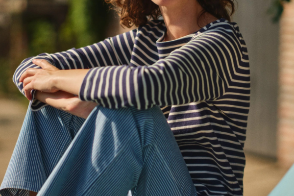 Woman wearing a classic navy and white Breton stripe boatneck shirt with blue striped pants.